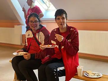 Zwei Spielerinnen sitzen auf einer Bank und essen.