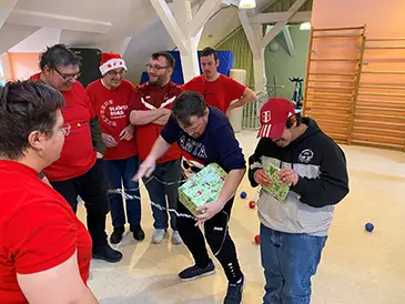 Menschen in Sportkleidung packen Weihnachtsgeschenke aus.